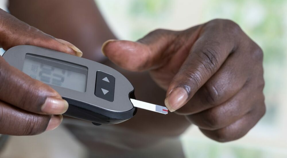 femme noire testant son diabète avec un glucomètre