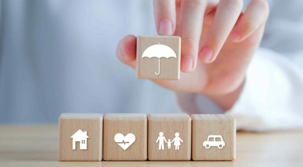 série de cube avec des icônes symbolisant la santé, la famille, la voiture, la maison. Au dessus une main tient un cube avec parapluie symbolisant la prévoyance