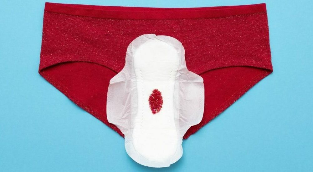 culotte rouge sur laquelle est posée une serviette hygiénique tachée de sang