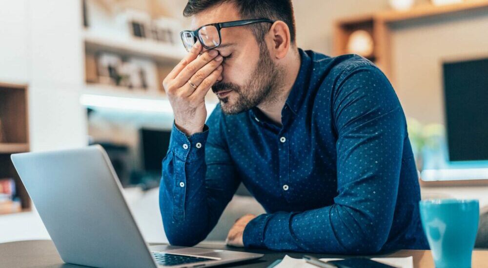 Homme fatigué et soucieux devant un ordinateur